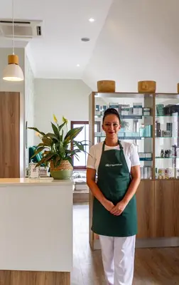 a woman wearing a green apron standing in a kitchen at Winelands Golf Lodges 1 in Onder-Papegaaiberg