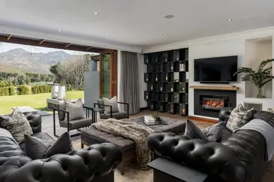 a living room with leather furniture and a fireplace at Franschhoek Homestead Manor House in Franschhoek