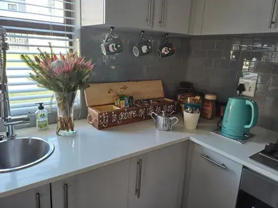 a kitchen counter with a sink and a vase of flowers at Sozo - our place at the ocean in Gordonʼs Bay