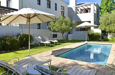 a pool with chairs and an umbrella next to a building at Holly Tree Franschhoek Accommodation in Franschhoek