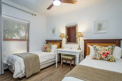 a bedroom with two beds and a desk and a window at Holly Tree Franschhoek Accommodation in Franschhoek
