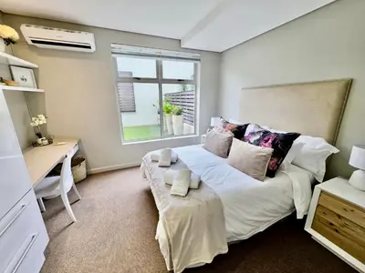 a bedroom with a bed with a desk and a window at Stay at Andringa Walk Luxury Apartment in Stellenbosch