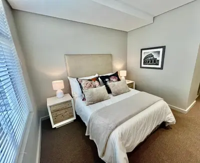 a bedroom with a bed with pillows and a window at Stay at Andringa Walk Luxury Apartment in Stellenbosch