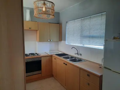 a kitchen with wooden cabinets and a sink and a window at Pips Place 203 in Strand