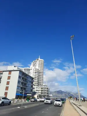 a large white building with cars parked on a street at Pips Place 203 in Strand