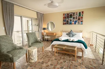 a bedroom with a bed and a chair and a table at Hillside Hideaways - With Pool in Hermanus