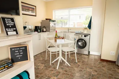 a kitchen with a table and a washing machine at Hillside Hideaways - With Pool in Hermanus