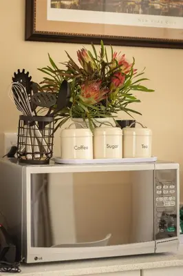a table with flowers on top of a microwave at Hillside Hideaways - With Pool in Hermanus