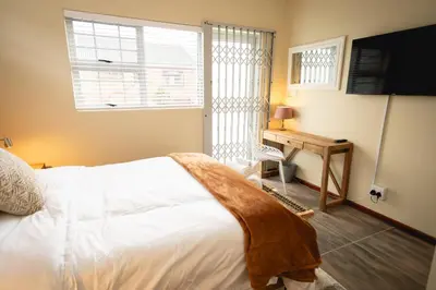 a bedroom with a bed and a window and a desk at Hillside Hideaways - With Pool in Hermanus