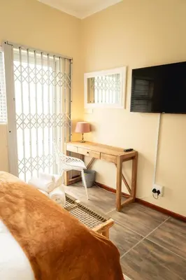 a living room with a desk and a television at Hillside Hideaways - With Pool in Hermanus