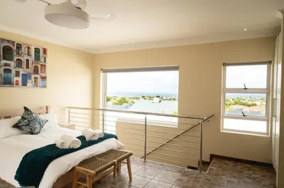a bedroom with a bed and a large window at Hillside Hideaways - With Pool in Hermanus
