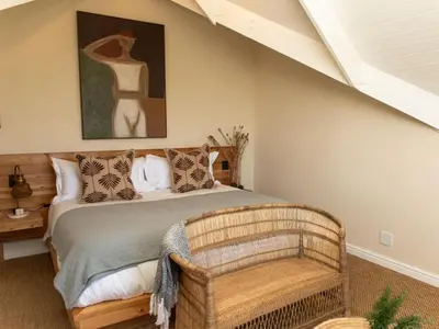 a bedroom with a bed with a chair and a painting at Little Villa by Ideas Cartel in Hermanus