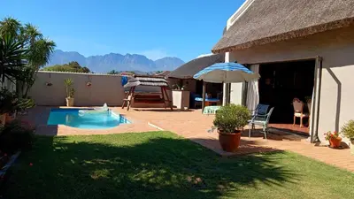 a house with a swimming pool and an umbrella at A gorgeous apartment with a pool view at Goedehoop, Strand, Western Cape in Strand