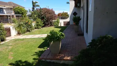 a brick walkway next to a house with potted plants at A gorgeous apartment with a pool view at Goedehoop, Strand, Western Cape in Strand