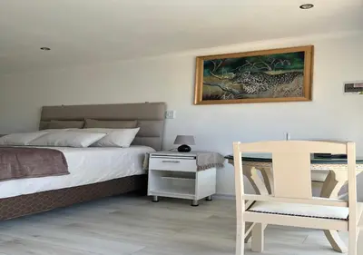 a bedroom with a bed and a table and a chair at Modern Studio with Pool, 5 mins from Beach in Cape Town
