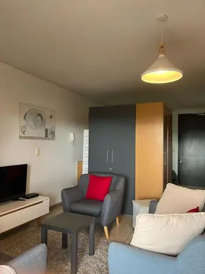 a living room with a couch and a red pillow at Century City Studio with Table Mountain Views in Cape Town