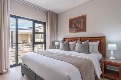 a bedroom with a large bed and a balcony at Oceanfront Escape with mountain views in Hermanus