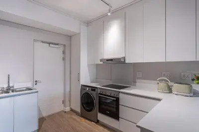 a kitchen with white cabinets and a washer and dryer at Oceanfront Escape with mountain views in Hermanus