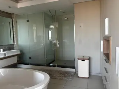 a bathroom with a tub and a glass shower at Luxury Penthouse -Crystal Towers in Cape Town