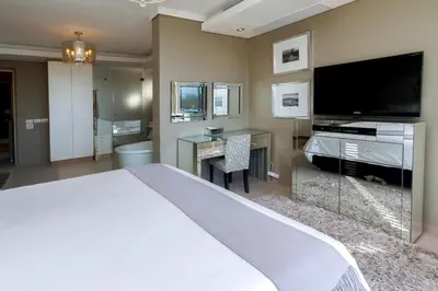 a bedroom with a large white bed and a flat screen tv at Luxury Penthouse -Crystal Towers in Cape Town