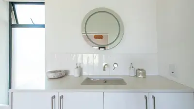 a white bathroom with a sink and a mirror at Franschhoek Homestead Cottage in Groendal