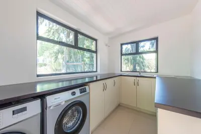 a laundry room with a washer and dryer and two windows at Franschhoek Homestead Cottage in Groendal