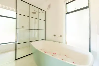 a white bathroom with a tub and a shower at Franschhoek Homestead Cottage in Groendal