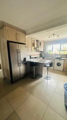 a kitchen with a refrigerator and a table and chairs at Hideaway Haven 2 in Cape Town