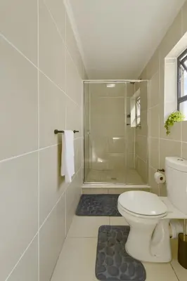 a bathroom with a shower and a toilet at Chic & Cozy Apartment with Pool, Gym & Balcony - The Sandown in Cape Town