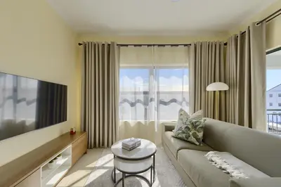 a living room with a couch and a large window at Chic & Cozy Apartment with Pool, Gym & Balcony - The Sandown in Cape Town