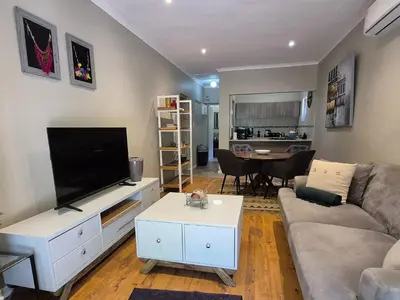 a living room with a couch and a flat screen tv at Mistys Apartment Durbanville in Durbanville