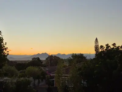 a sunset over a city with mountains in the background at Mistys Apartment Durbanville in Durbanville