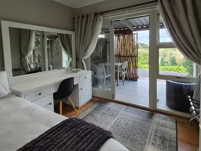 a bedroom with a bed and a desk and a balcony at Mistys Apartment Durbanville in Durbanville