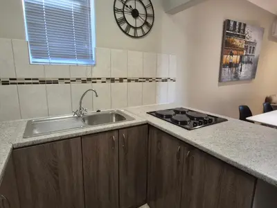 a kitchen with a sink and a clock on the wall at Mistys Apartment Durbanville in Durbanville