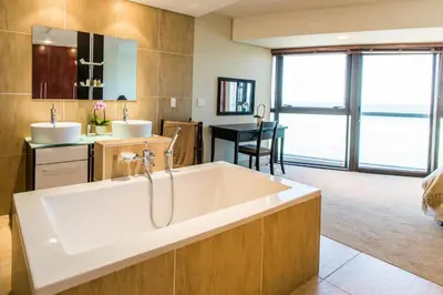 a bathroom with a large tub and a sink at Loddey's Self Catering Apartments - by Beach Collection in Strand