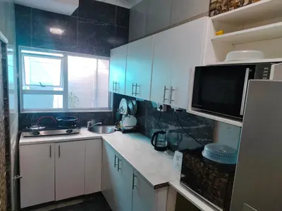 a kitchen with white cabinets and a sink and a microwave at Boblodge in Cape Town