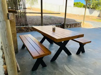 a wooden picnic table and benches on a patio at Rissie's Place in Gordonʼs Bay