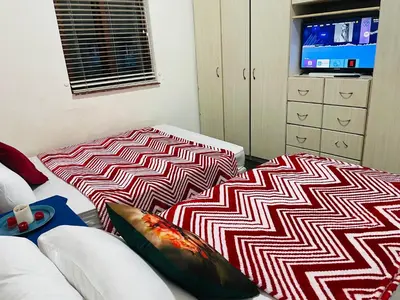 a living room with two beds and a tv at ANNIKA B&B Claremont in Cape Town