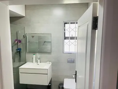 a white bathroom with a sink and a mirror at ANNIKA B&B Claremont in Cape Town