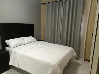 a bedroom with a white bed with a black headboard at Spring forth guest house in De Grendel