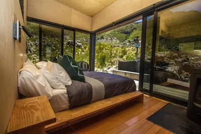 a bedroom with a bed in a room with large windows at Skaam Cabin Luxe Hideaway with a Naughty Side in Wolseley