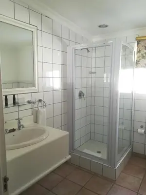 a white bathroom with a shower and a sink at Zevenwacht Cottages in Kuilsrivier