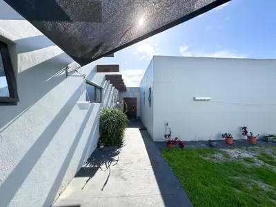 a white house with a courtyard with green grass at Spacious Shared 3-Bedroom Villa Near Bloubergstrand Beach with Pool & Free Wi-Fi in Cape Town