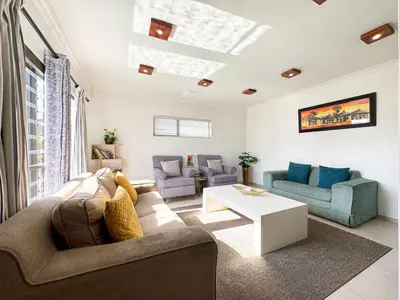 a living room with a couch and chairs and a table at Spacious Shared 3-Bedroom Villa Near Bloubergstrand Beach with Pool & Free Wi-Fi in Cape Town