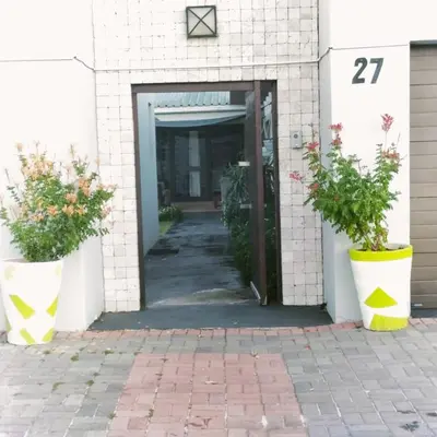 a door to a building with two potted plants at Spacious Shared 3-Bedroom Villa Near Bloubergstrand Beach with Pool & Free Wi-Fi in Cape Town