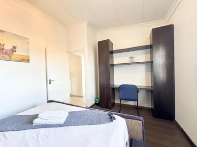 a bedroom with a bed and a blue chair at Spacious Shared 3-Bedroom Villa Near Bloubergstrand Beach with Pool & Free Wi-Fi in Cape Town