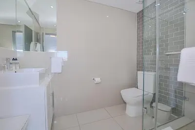a bathroom with a toilet and a glass shower at Aquarius 2 Bedroom Luxury Apartment in Cape Town