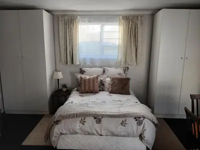 a bedroom with a bed with pillows and a window at Cozy, self-catering Garden Flat in Cape Town