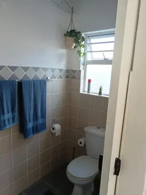 a bathroom with a toilet and blue towels at Cozy, self-catering Garden Flat in Cape Town