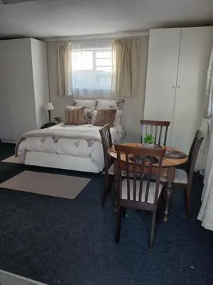 a bedroom with a bed and a table and chairs at Cozy, self-catering Garden Flat in Cape Town